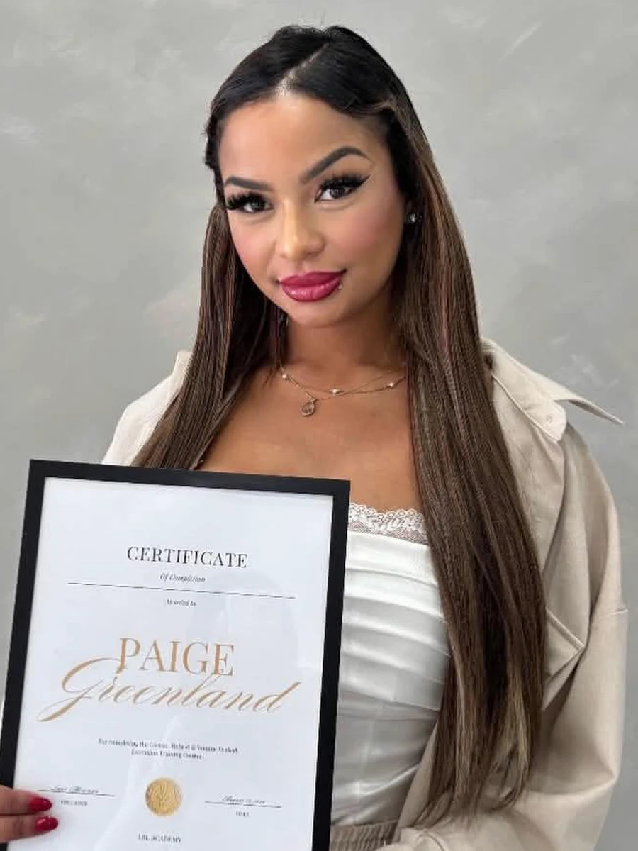 Paige Greenland, owner of Luxe Flutter, holding her certificate of completion in eyelash extension training.
